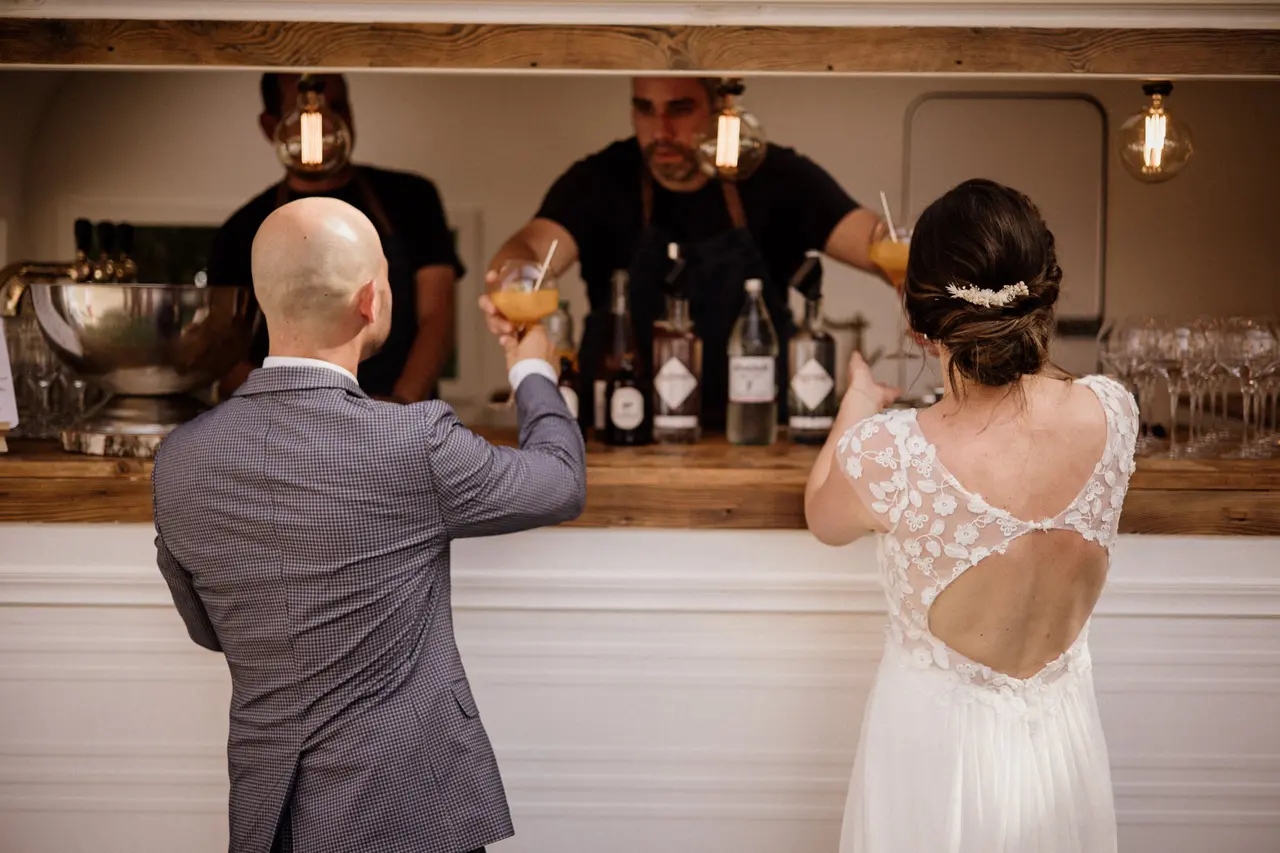 Couple de mariés de dos devant la caravane Louise Nomad Bar