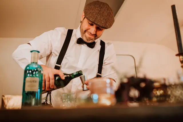 Préparation de cocktail dans le drink truck Louise Nomad Bar par un barman en costume